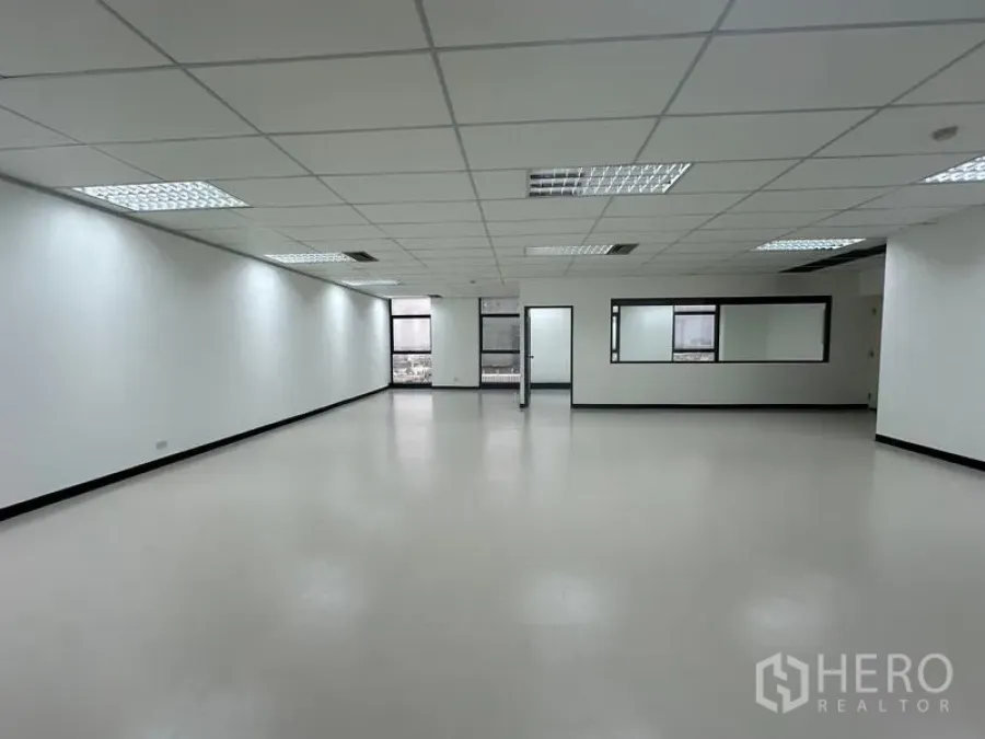 Office Space for rent - Open office space with windows on two sides and a doorway to a private room.