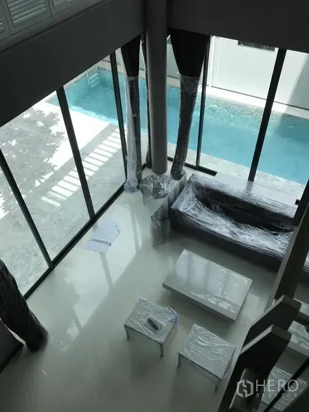 Detached House for rent in Bang Kapi, Bangkok - Double-height living room with floor-to-ceiling windows overlooking a private lap pool.