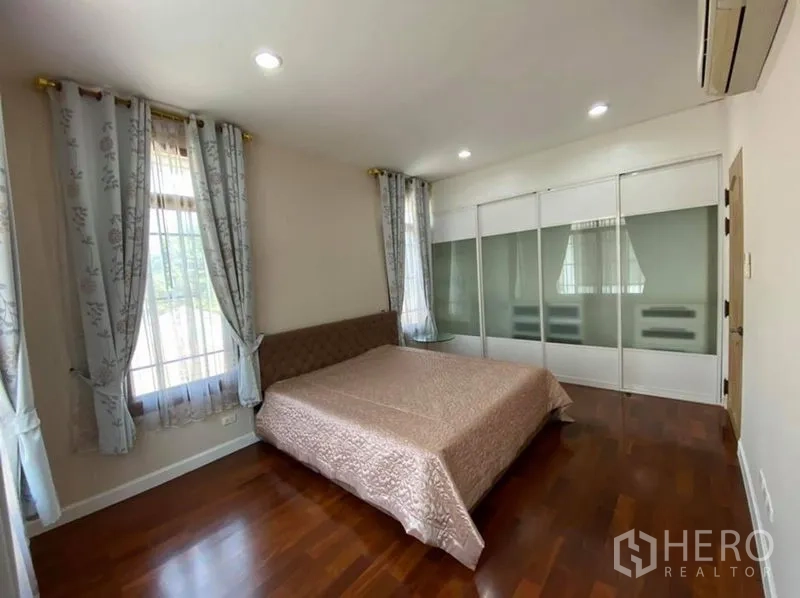 Detached House for rent in Bang Phli, Samut Prakan - Sunlit bedroom with large windows, frosted glass sliding wardrobe and wood flooring.