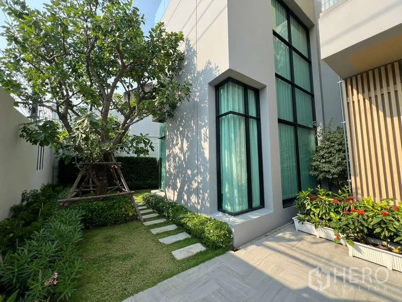 บ้าน ขายในSuan Luang, Bangkok - สวนร่มรื่นและหน้าต่างกระจกสูงมุมอาคาร