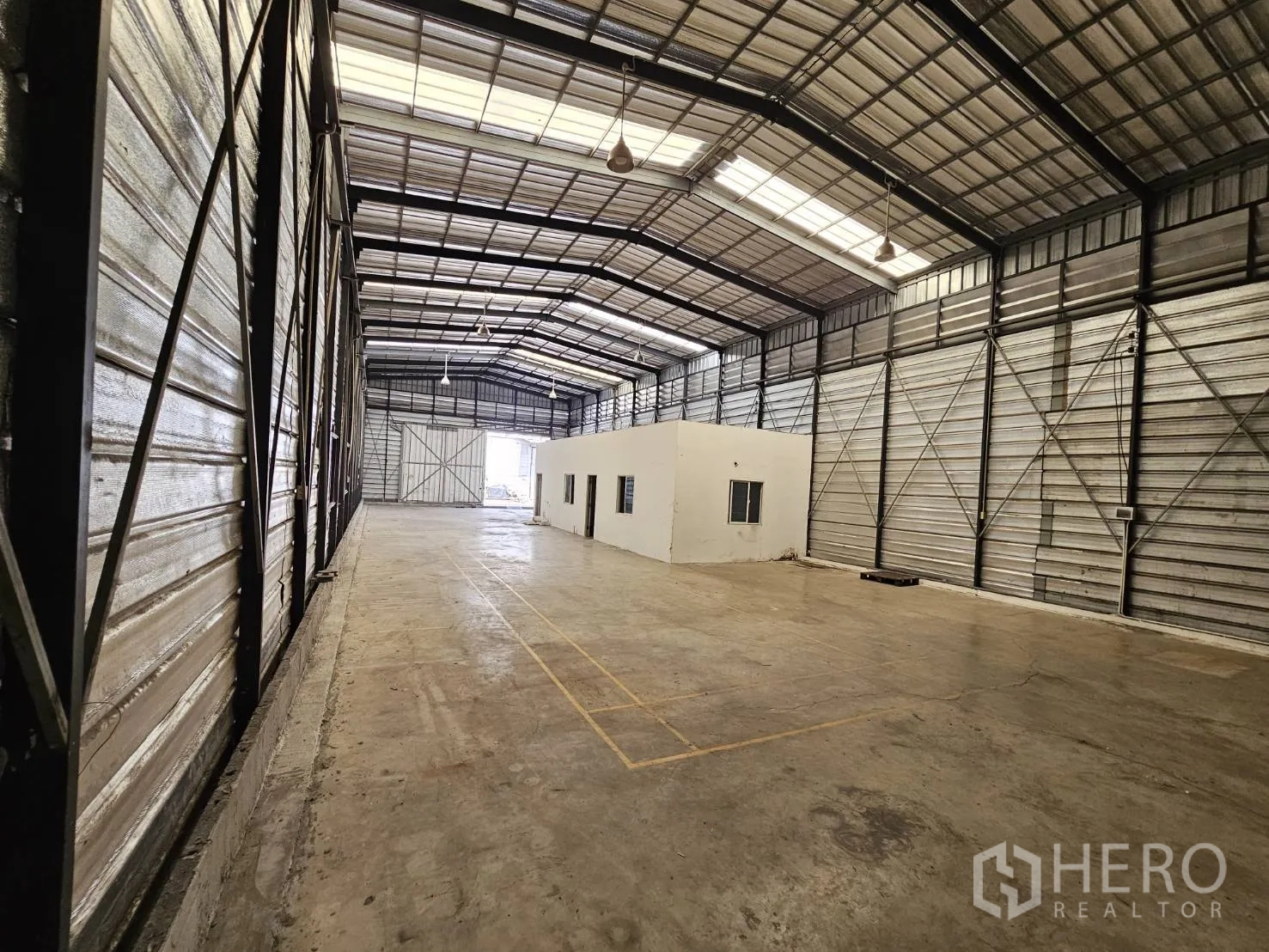 仓库 for rent in Bang Phli, Samut Prakan - 仓库纵深视角，中央有办公室单元，尽端为大型滑动门。