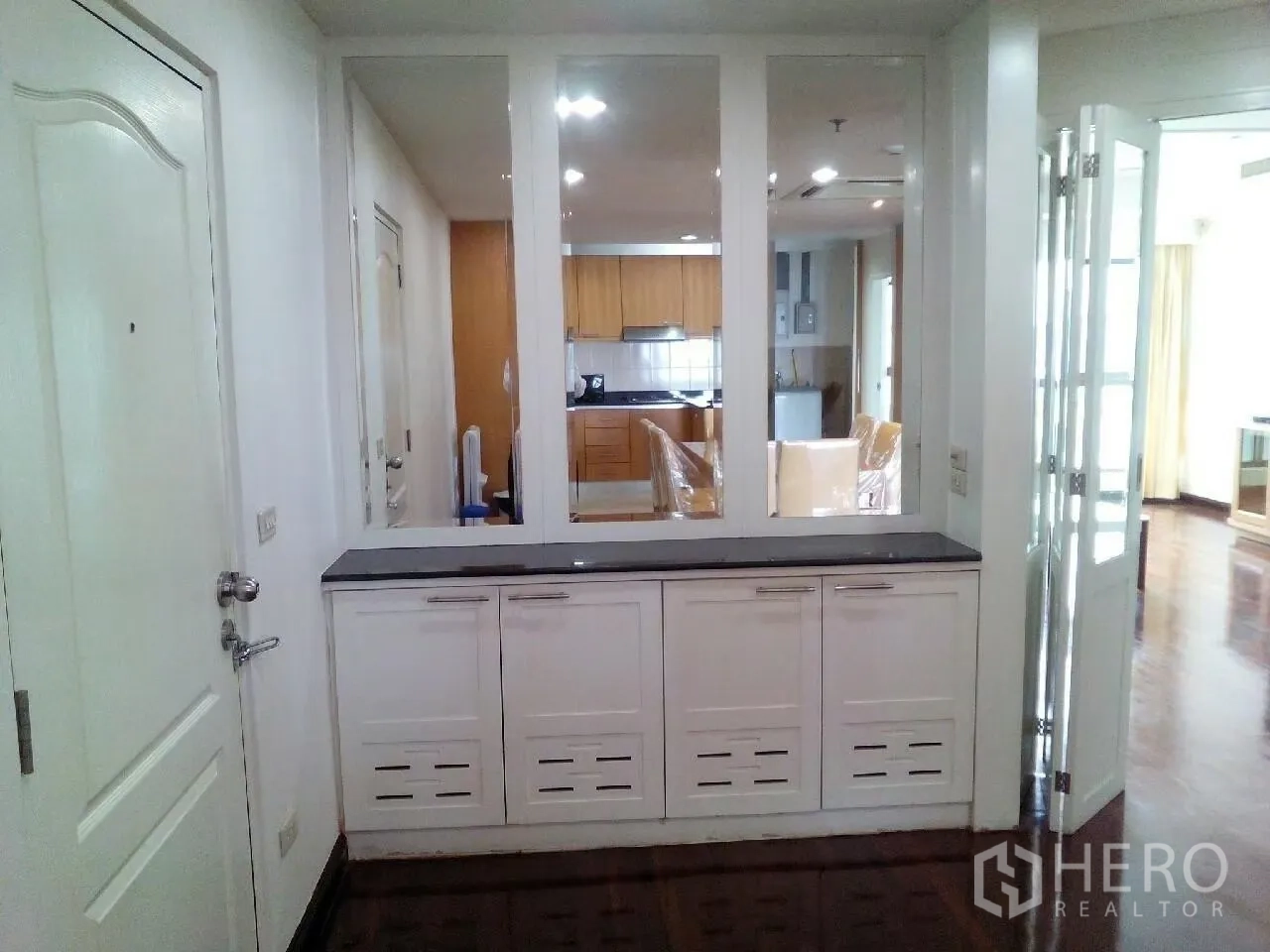 Condominium for rent in Phaya Thai, Bangkok - Entry hall featuring white built-in storage with three large mirrors and dark wood floors.
