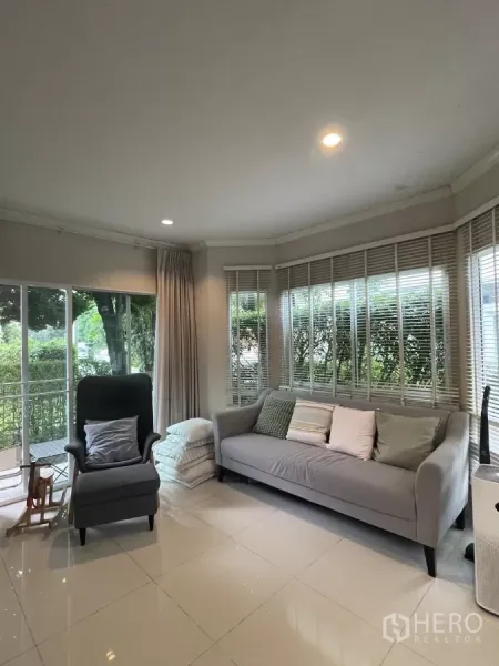 บ้าน ขายในMin Buri, Bangkok - ห้องนั่งเล่นสว่าง มีกระจกบานใหญ่รอบมุม โซฟาและเก้าอี้พักผ่อน เปิดมองสวน