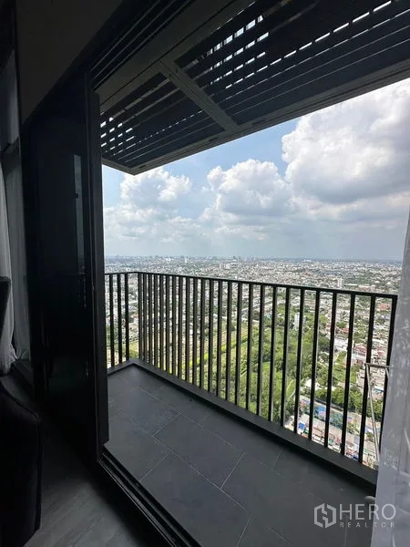 Condominium for rent in Phra Khanong, Bangkok - Covered balcony with black railing showcasing expansive city and green park views.
