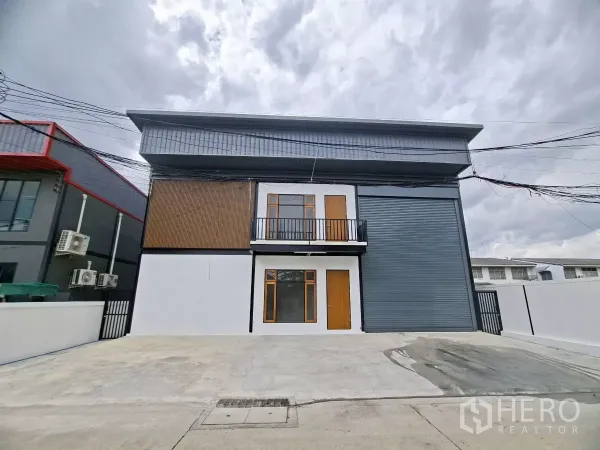 Warehouse for rent in Lam Luk Ka, Pathum Thani - Modern mini-factory warehouse exterior in Lat Sawai, Lam Luk Ka with large roller shutter, balcony office and wide concrete parking apron.