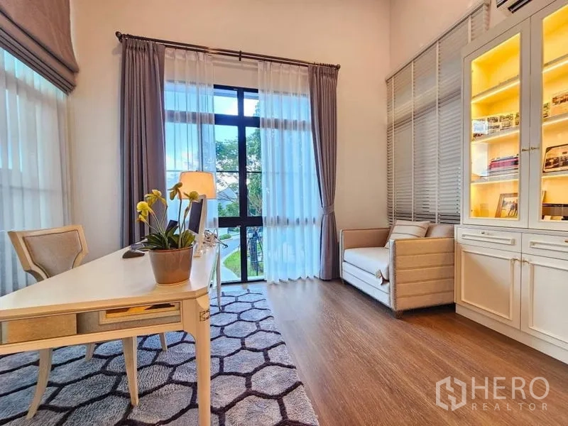 Detached House for rent or sale in Saphan Sung, Bangkok - Bright home office with desk, tall windows and illuminated shelving.