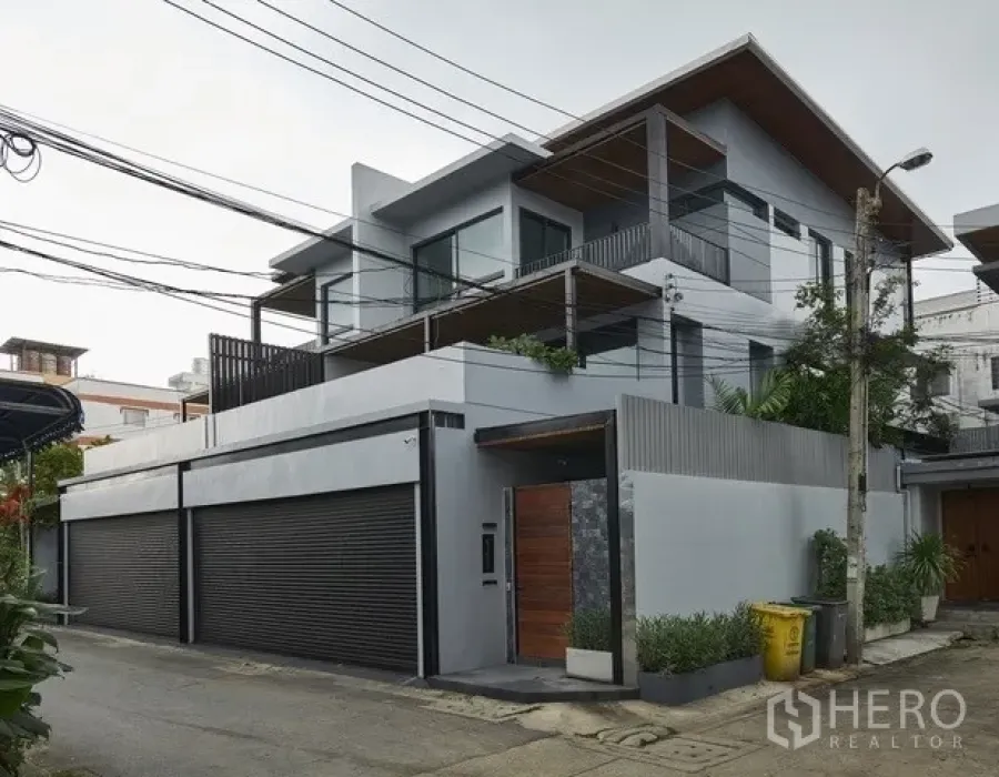 Townhouse for sale in Watthana, Bangkok - Another view of the modern townhouse facade with high privacy wall and wooden entry gate.