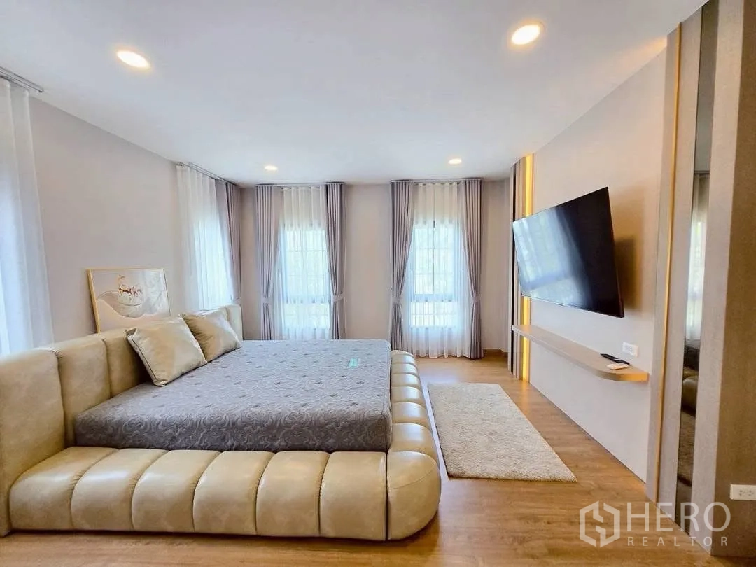 Detached House for rent in Bang Phli, Samut Prakan - Master bedroom with wall-mounted TV, warm lighting, and corner windows.