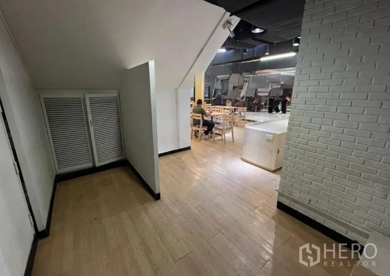 Retail Space for rent in Watthana, Bangkok - Hallway with under-stair storage leading to a seating area with wooden flooring inside a retail space.