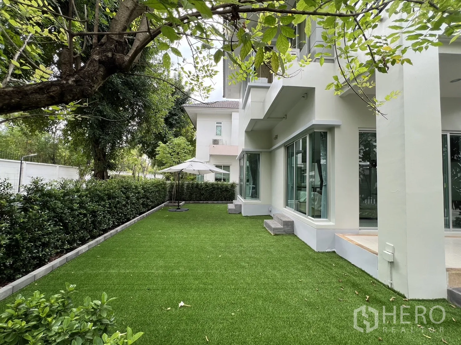 Detached House for rent in Saphan Sung, Bangkok - Wide green garden with trees and patio umbrella next to the house.