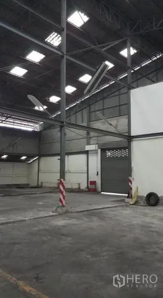 Warehouse for rent in Bang Phli, Samut Prakan - Spacious interior with steel columns, high roof, skylights and a roller door.