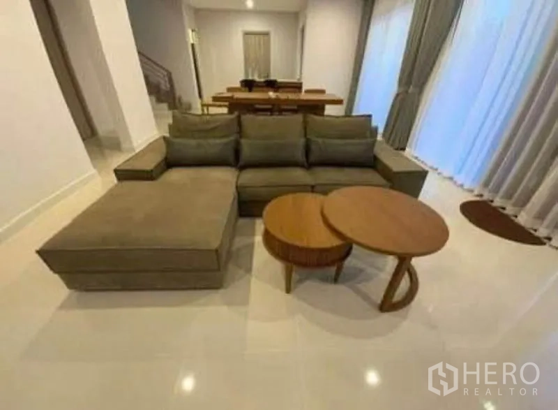 Detached House for rent - Open-plan lounge with sectional sofa and nesting round coffee tables.