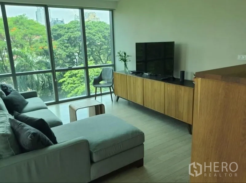 公寓 出租或出售在Watthana, Bangkok - 转角客厅，贵妃位沙发与木质电视柜，环景树海视野