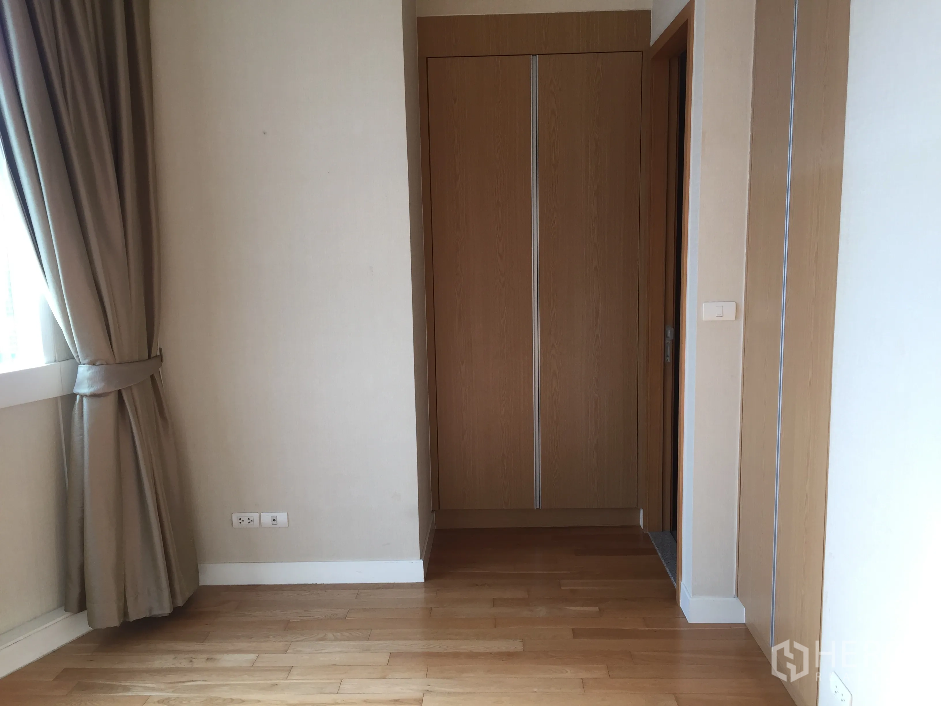 Condominium for rent in Khlong Toei, Bangkok - Bedroom corner with large window, blackout curtains, and a built-in wardrobe.