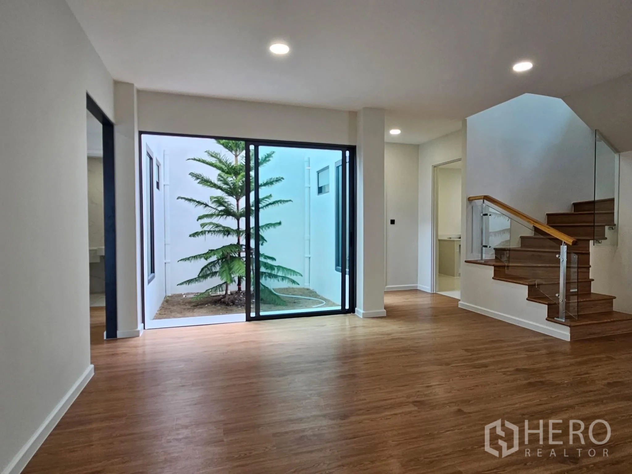 独栋房屋 for sale in Lat Phrao, Bangkok - 起居区通过大幅推拉门连接种有树的私家庭院。