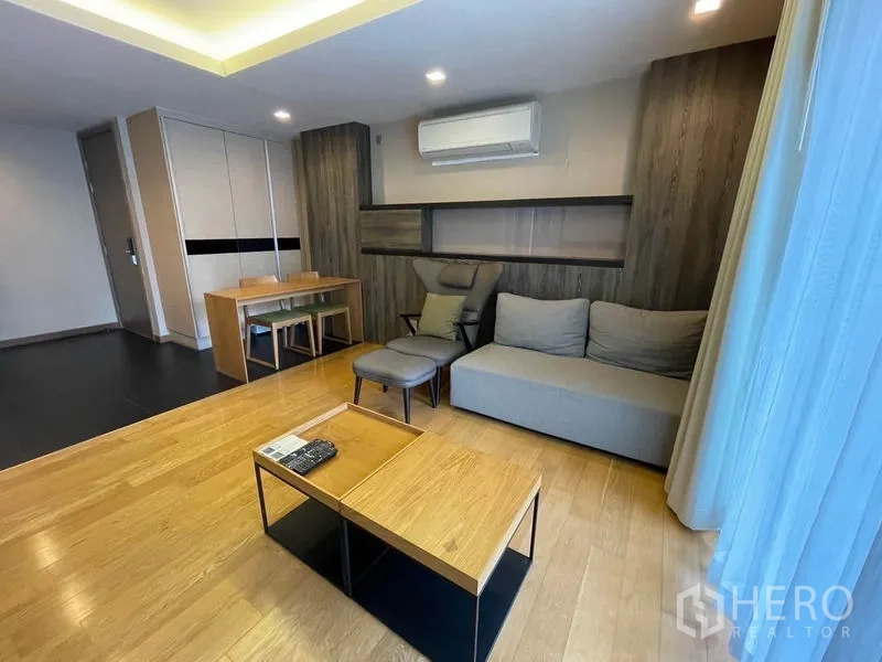 公寓 出售在Watthana, Bangkok - 客厅有空调、沙发与大窗，木地板通透明亮。
