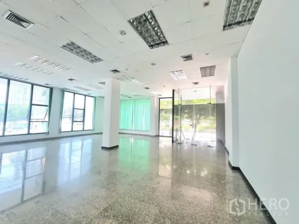 零售空间 出租在Sathon, Bangkok - 店铺明亮角落，玻璃入户门、吊顶照明，落地窗配绿色百叶帘。