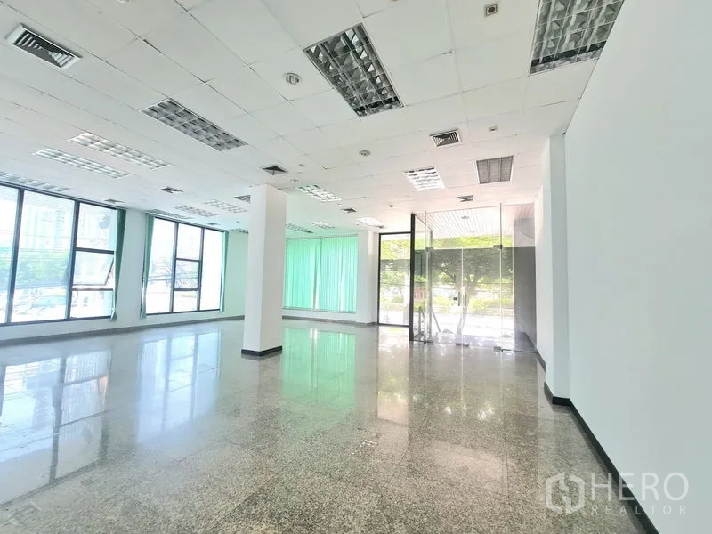 零售空间 出租在Sathon, Bangkok - 店铺明亮角落，玻璃入户门、吊顶照明，落地窗配绿色百叶帘。