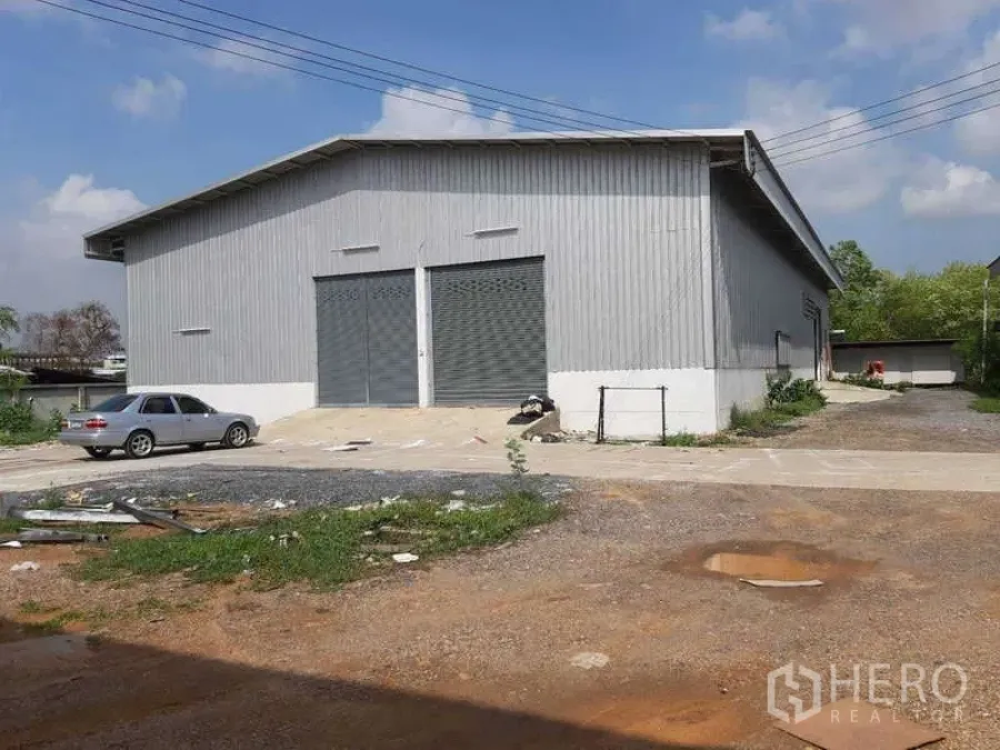 货栈 出租在Khlong Luang, Pathum Thani - 金属外墙仓库外观，双卷帘门，车道与停车区进出方便。