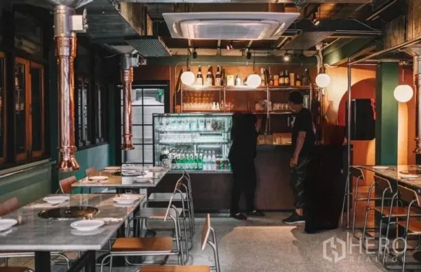 独立式住宅 出售在Khlong Toei, Bangkok - 吧台区配饮料冷柜与置物架及现代照明，旁边摆放整齐的餐桌。