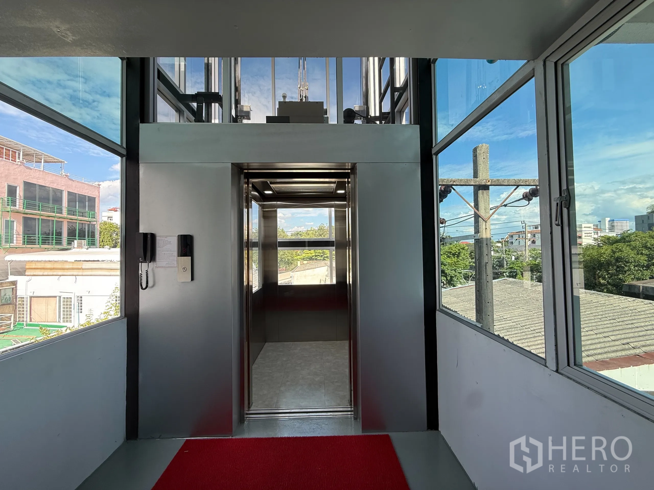 办公空间 出租在Wang Thonglang, Bangkok - 玻璃围合的电梯前厅，可见城市景观，现代电梯直达办公楼层。