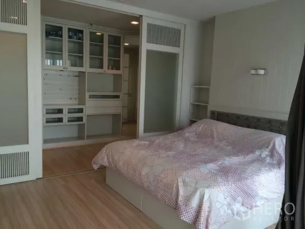 Condominium for rent in Khlong Luang, Pathum Thani - Bedroom with built-in wardrobes, sliding glass doors, wood flooring and a large bed in neutral tones.