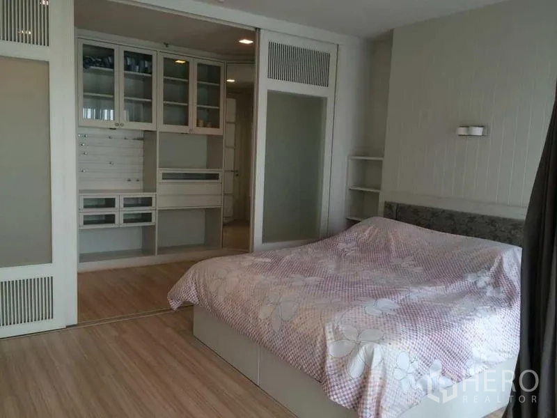 Condominium for rent in Khlong Luang, Pathum Thani - Bedroom with built-in wardrobes, sliding glass doors, wood flooring and a large bed in neutral tones.