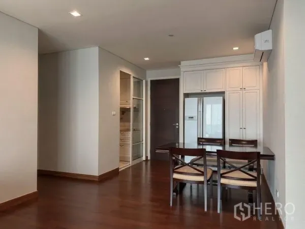 Condominium for rent in Watthana, Bangkok - Dining area with wooden floors, built-in cabinets and a stainless fridge beside the kitchen.