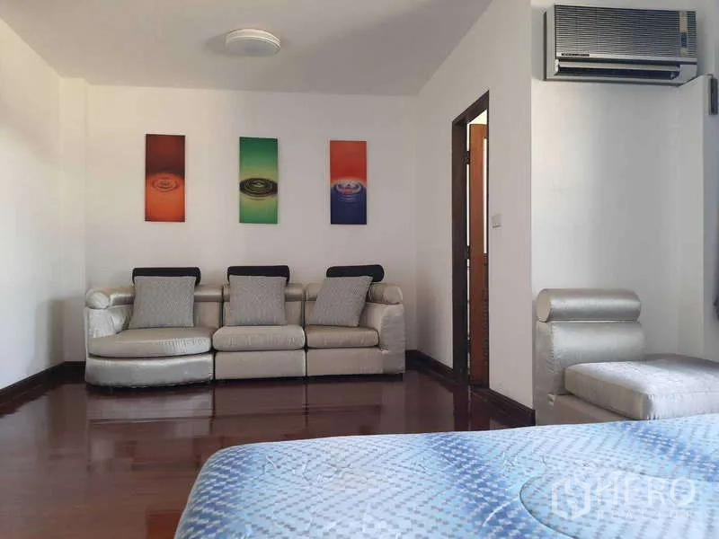 Townhouse for rent in Khlong Toei, Bangkok - Upper-floor sitting area with silver sofa set and wall art.