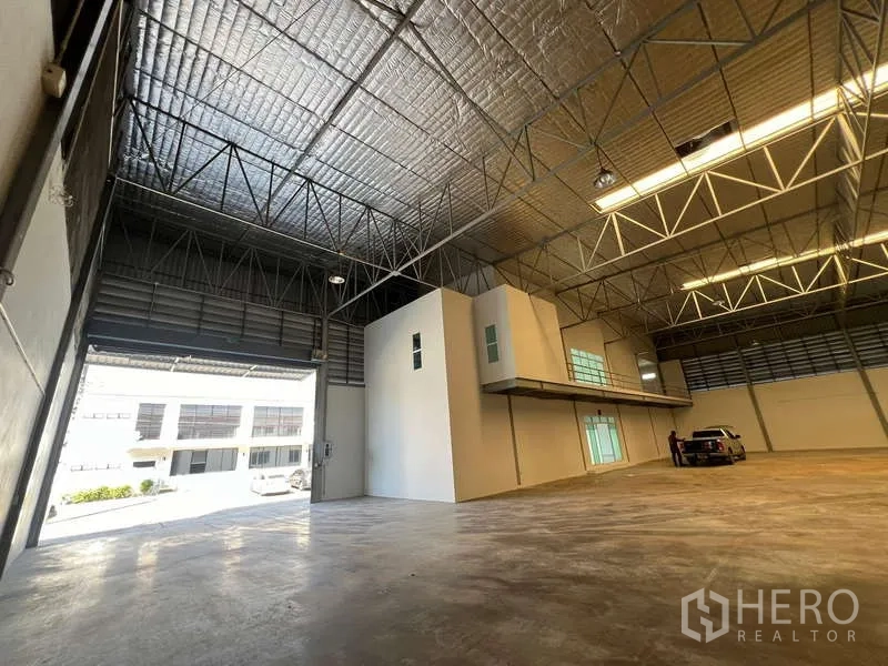 Warehouse for rent in Prawet, Bangkok - Warehouse hall with mezzanine offices and open loading door, vehicle inside.