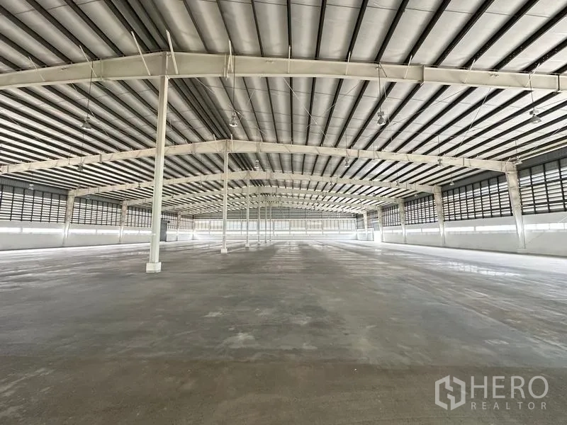 Factory for rent in Pathum Thani - Open production hall with high ceilings, ventilation louvers, and lighting.