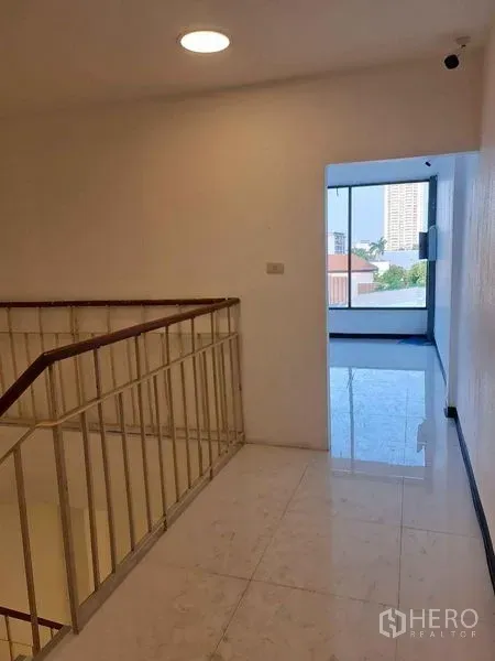 店屋 出售在Watthana, Bangkok - 通罗店屋的楼梯平台，白色瓷砖地面，通向采光充足的房间与城市景观。