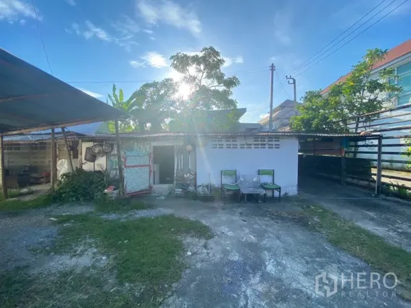 Warehouse for rent in Suan Luang, Bangkok - Auxiliary outbuilding and covered storage area inside the compound with open yard, chairs and trees.
