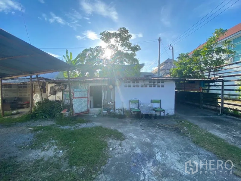 Warehouse for rent in Suan Luang, Bangkok - Auxiliary outbuilding and covered storage area inside the compound with open yard, chairs and trees.