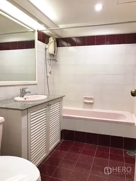 Condominium for rent or sale in Watthana, Bangkok - Bathroom featuring white and maroon tiles, bathtub with shower heater and granite-topped sink.