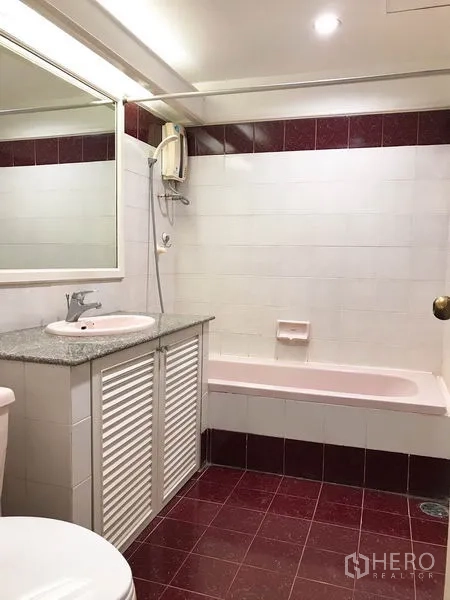 Condominium for rent or sale in Watthana, Bangkok - Bathroom featuring white and maroon tiles, bathtub with shower heater and granite-topped sink.