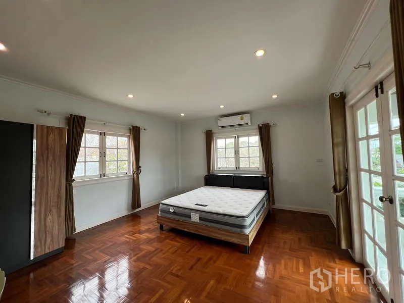 Detached House for rent in Bang Phli, Samut Prakan - Spacious master bedroom with parquet floor, AC, recessed lights, and French doors.