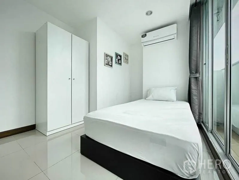 Condominium for rent in Khlong Toei, Bangkok - Single bedroom from another angle with white wardrobe and sliding glass doors.
