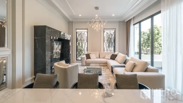 Detached House for rent or sale in Bang Kapi, Bangkok - Bright living room with L‑shaped sofa, marble TV wall, large windows and a crystal chandelier.