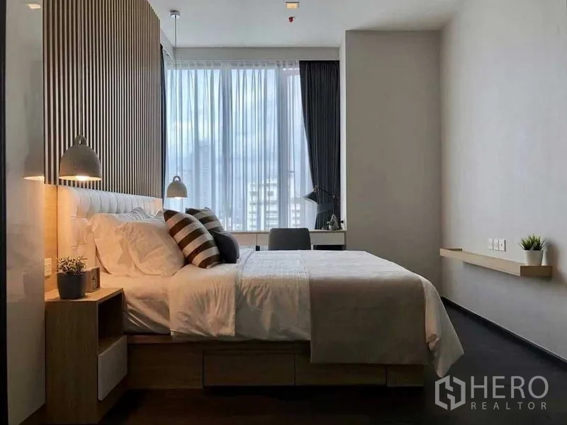 公寓 出租在Watthana, Bangkok - 现代卧室，带大床、木质条形床头、吊灯与落地窗旁的书桌。