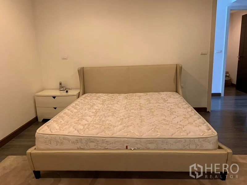 คอนโด ให้เช่าในPathum Wan, Bangkok - ห้องนอนหลักเตียงบุหนังพร้อมโต๊ะข้าง เต็มไปด้วยโทนสีอบอุ่น