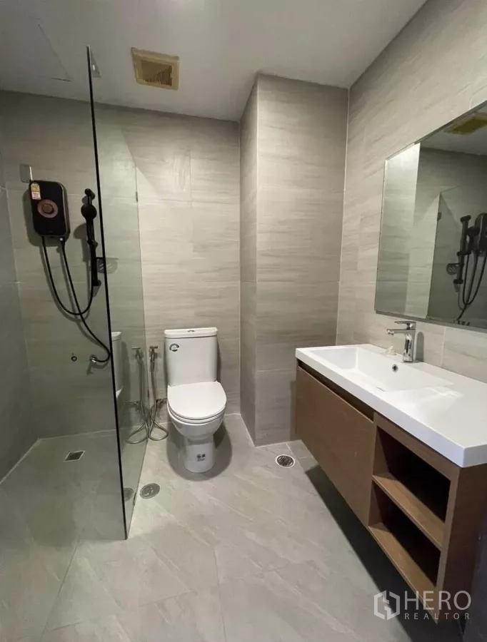 Condominium for rent in Sathon, Bangkok - Modern bathroom with glass shower, vanity, and toilet.