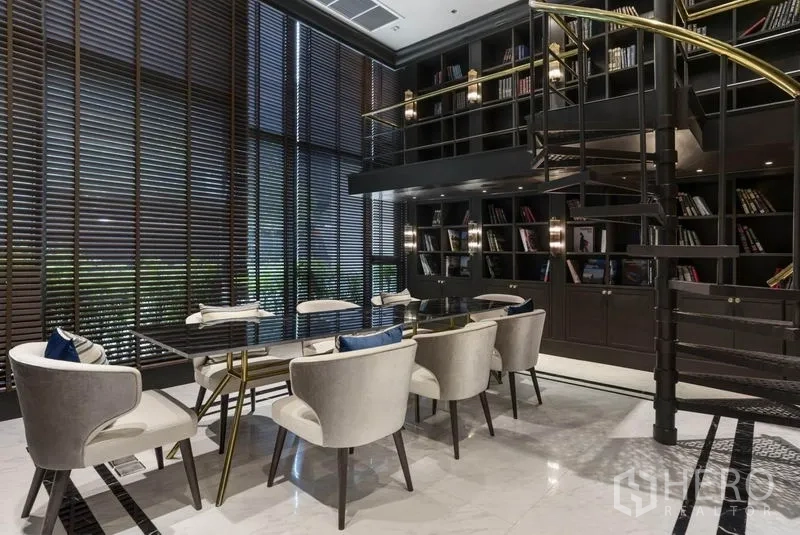 Condominium for sale in Pathum Wan, Bangkok - Luxury condominium library lounge with double-height bookshelves, spiral staircase and seating.