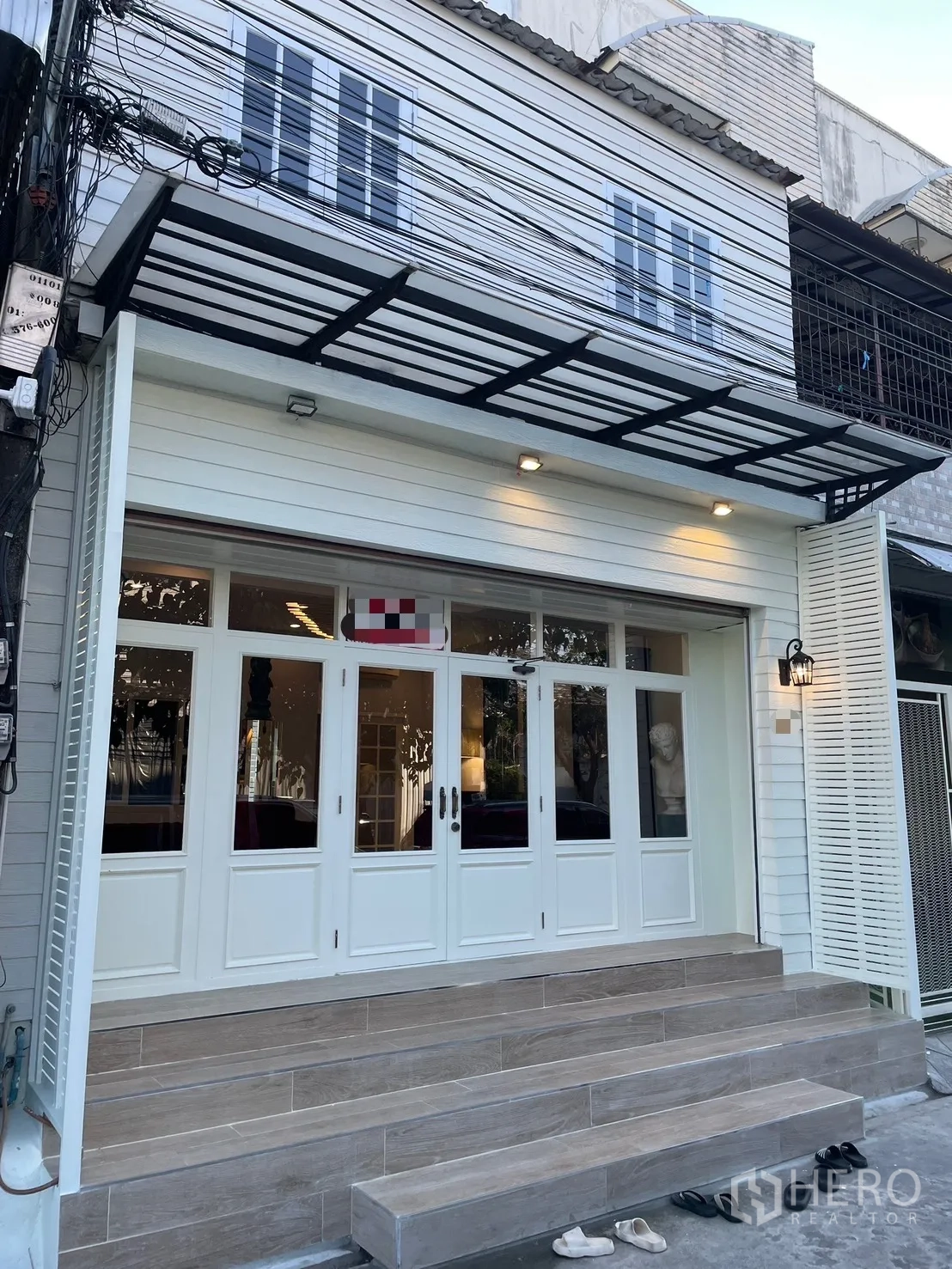 店屋 for rent in Bang Kapi, Bangkok - 临街商铺外立面，白色门面，玻璃大门，金属雨棚与宽台阶。