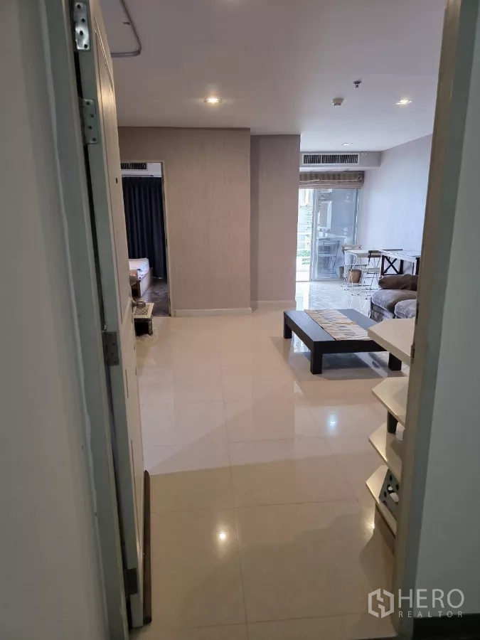 公寓 出租在Khlong Toei, Bangkok - 入口走廊通向明亮客厅，亮面地砖，可见卧室门与阳台，靠近BTS澎蓬站的一居室公寓。