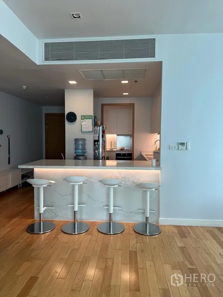 Condominium for rent in Khlong Toei, Bangkok - Modern kitchen with white marble breakfast bar and four bar stools.