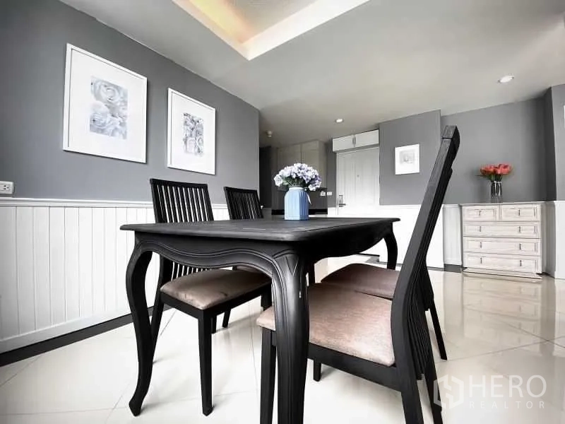 Condominium for rent in Khlong Toei, Bangkok - Dining area with black wooden table, four chairs and wall art accents.
