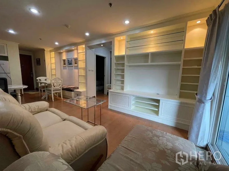 Condominium for rent - Open-plan living area with illuminated built-in shelves and dining corner.