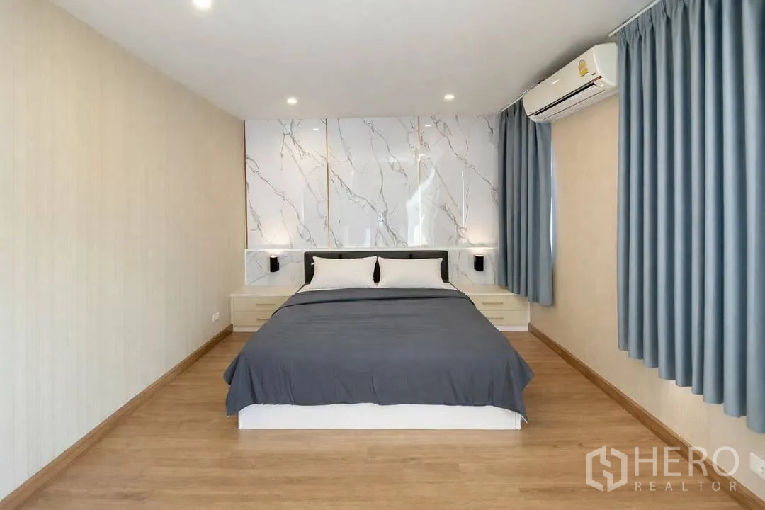独栋房屋 for rent in Suan Luang, Bangkok - 宽敞卧室，双人床，大理石纹背景墙，蓝色窗帘与空调。