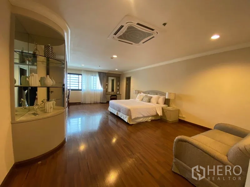 公寓 出租在Watthana, Bangkok - 超大主卧，木地板、双人床、吊顶空调与弧形展示柜。